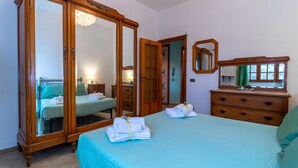 Un dormitorio con cama, armario, cómoda, espejo y puerta que da a otra habitación.