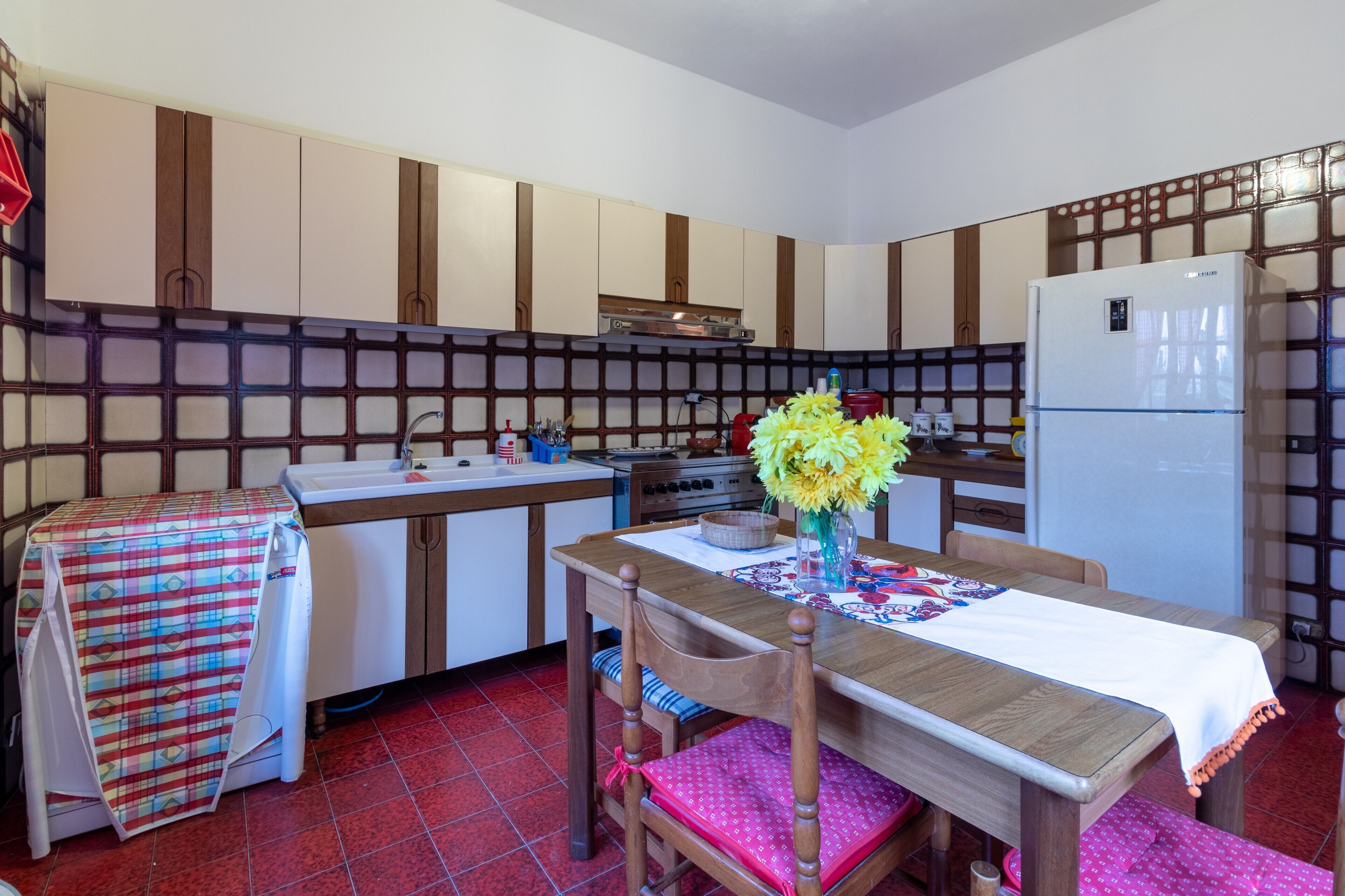 Une cuisine compacte comprenant une table à manger, des chaises, un réfrigérateur et un évier.