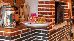 Una chimenea de ladrillo con un plato decorativo, una botella de vino y figuras de cerámica.