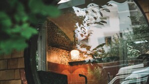 Ein runder Spiegel, der einen Raum mit Wandmuster, einer Lampe und einem Stuhl reflektiert.