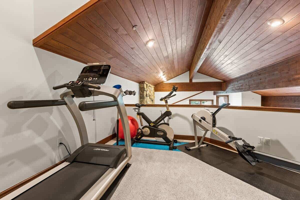 Une salle de sport à domicile équipée d’un tapis de course, d’un vélo d’appartement et d’un appareil elliptique.
