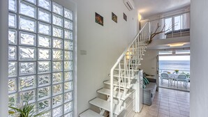 A staircase with white railings leading to a balcony with a view of the sea.