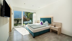 A modern bedroom with a bed, bedside table, and a TV mounted on the wall. - Apartment "Weinreichhof Marie & Max" with Mountain View, Private Terrace & Wi-Fi (Ciardes)