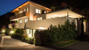 Una casa moderna de dos pisos con balcón, ventanas amplias y una entrada bien iluminada.
