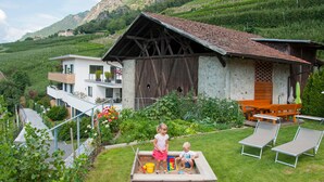 Una casa con un granero de madera, una piscina y un jardín con vistas a las montañas.