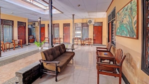 A spacious lobby with a sofa, dining table, chairs, and a large painting on the wall. - SPOT ON 92028 Hotel Surya Near Pelabuhan Gilimanuk (Melaya)
