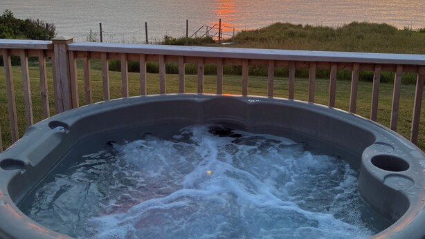 Een jacuzzi met uitzicht op de ondergaande zon boven de oceaan.
