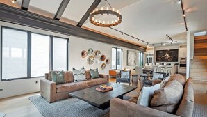 Ein geräumiges Wohnzimmer mit einer großen Sofagarnitur, einem Couchtisch sowie einer Essecke mit Fernseher und Küchengeräten.