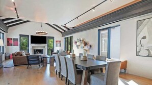 Ein geräumiger Wohnbereich mit Kamin, einem Esstisch mit Stühlen und einem großen Fenster für natürliches Licht.