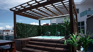 Un bain à remous avec des marches, une pergola en bois et une haie verdoyante.