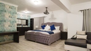 Une chambre à coucher avec un grand lit, un bureau, une commode et une coiffeuse avec un miroir.
