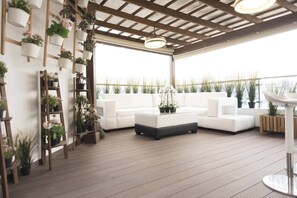 Un espace extérieur aménagé avec un salon de jardin, comprenant un canapé blanc, une table basse et des plantes en pot.