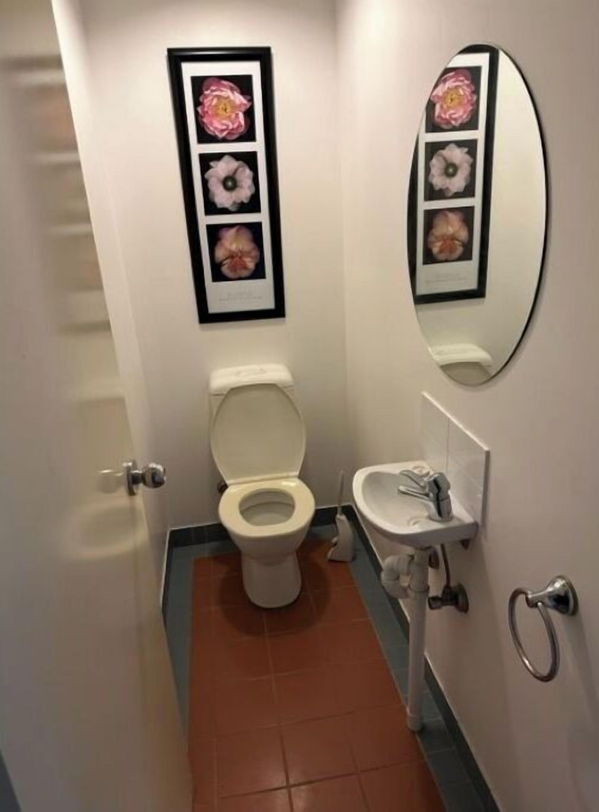 A bathroom with a toilet, sink, and a framed floral artwork above the toilet.