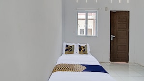 Een kamer met een bed, twee kussens, een raam en een deur.