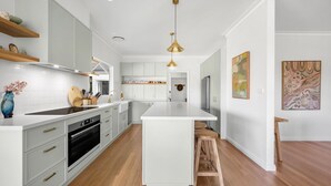 A modern kitchen with white cabinetry, a central island, wooden flooring, and pendant lighting. - Hygge House - Kangaroo valley (Kangaroo Valley)