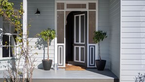 A house with a porch, two potted plants, a door, and a wall-mounted light fixture. - Hygge House - Kangaroo valley (Kangaroo Valley)