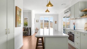 A modern kitchen with a central island, white cabinetry, and a hanging pendant light. - Hygge House - Kangaroo valley (Kangaroo Valley)