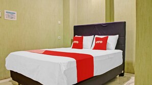 Quarto de hotel com cama, paredes verdes e um letreiro na parede.