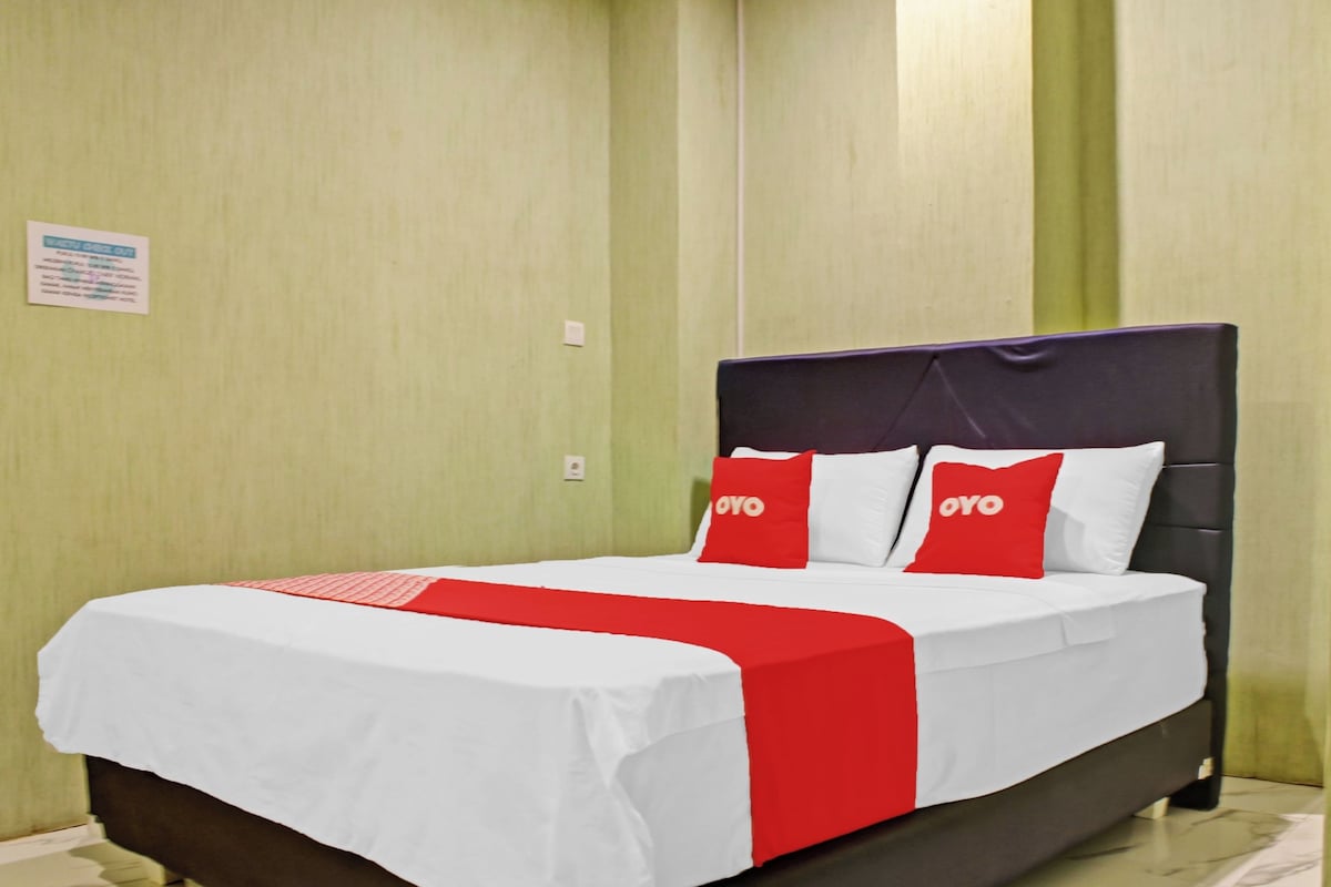 A hotel room with a bed, green walls, and a sign on the wall.