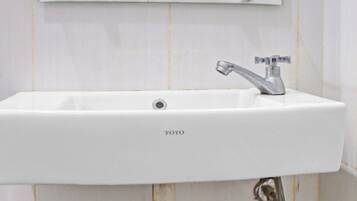 A white bathroom sink with a glass shelf above it, a mirror, and a Toto-branded faucet.