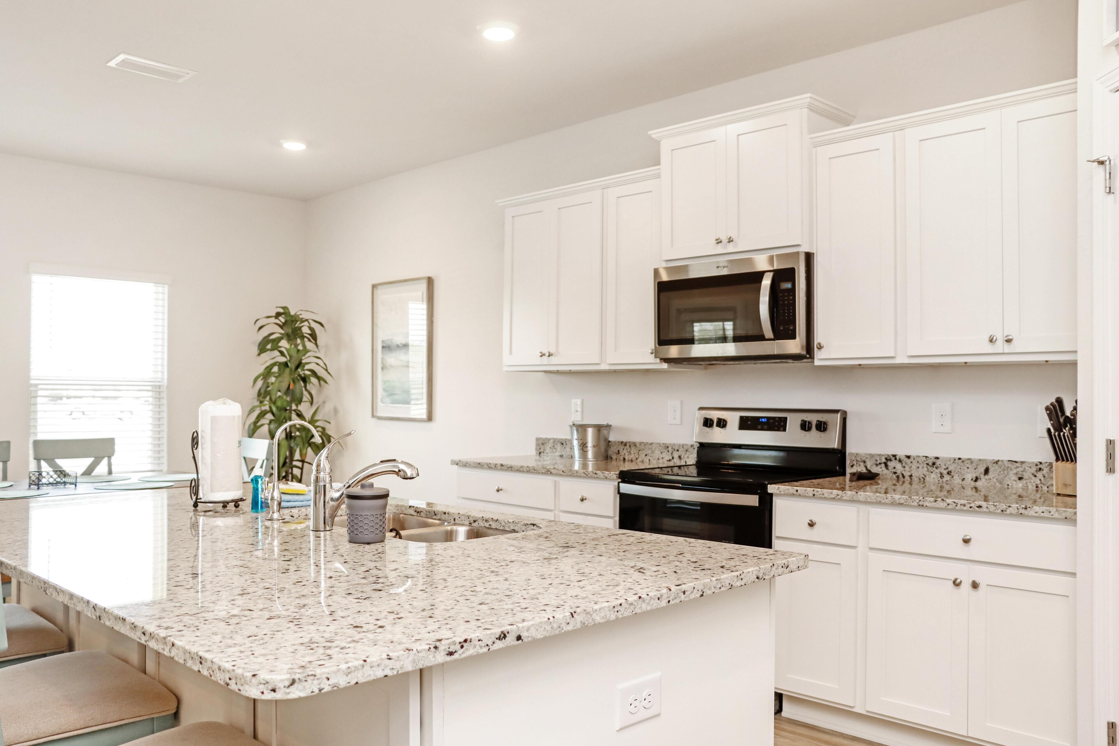 A kitchen with white cabinets, a granite countertop, stainless steel appliances, and a sink.
