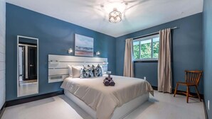 Een slaapkamer met een groot bed, een nachtkastje, een spiegel en een raam met gordijnen.
