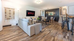 Een moderne woonkamer met een bank, salontafel en een televisie waarop 'NETFLIX' wordt getoond.