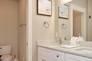A bathroom with a toilet, two sinks, a mirror, and a towel rack. - The Great White 1 (Port St. Joe)