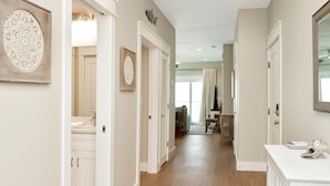 A hallway with white doors, a wooden floor, and a dining area in the background. - The Great White 1 (Port St. Joe)