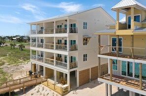 A multi-story beachfront building with balconies, a covered outdoor seating area, and a sandy beach in the background. - The Great White 1 (Port St. Joe)