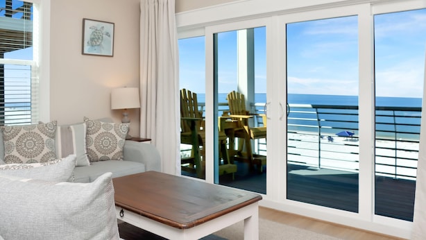 A room with a sofa, a coffee table, and a view of the ocean through large windows. - The Great White 1 (Port St. Joe)