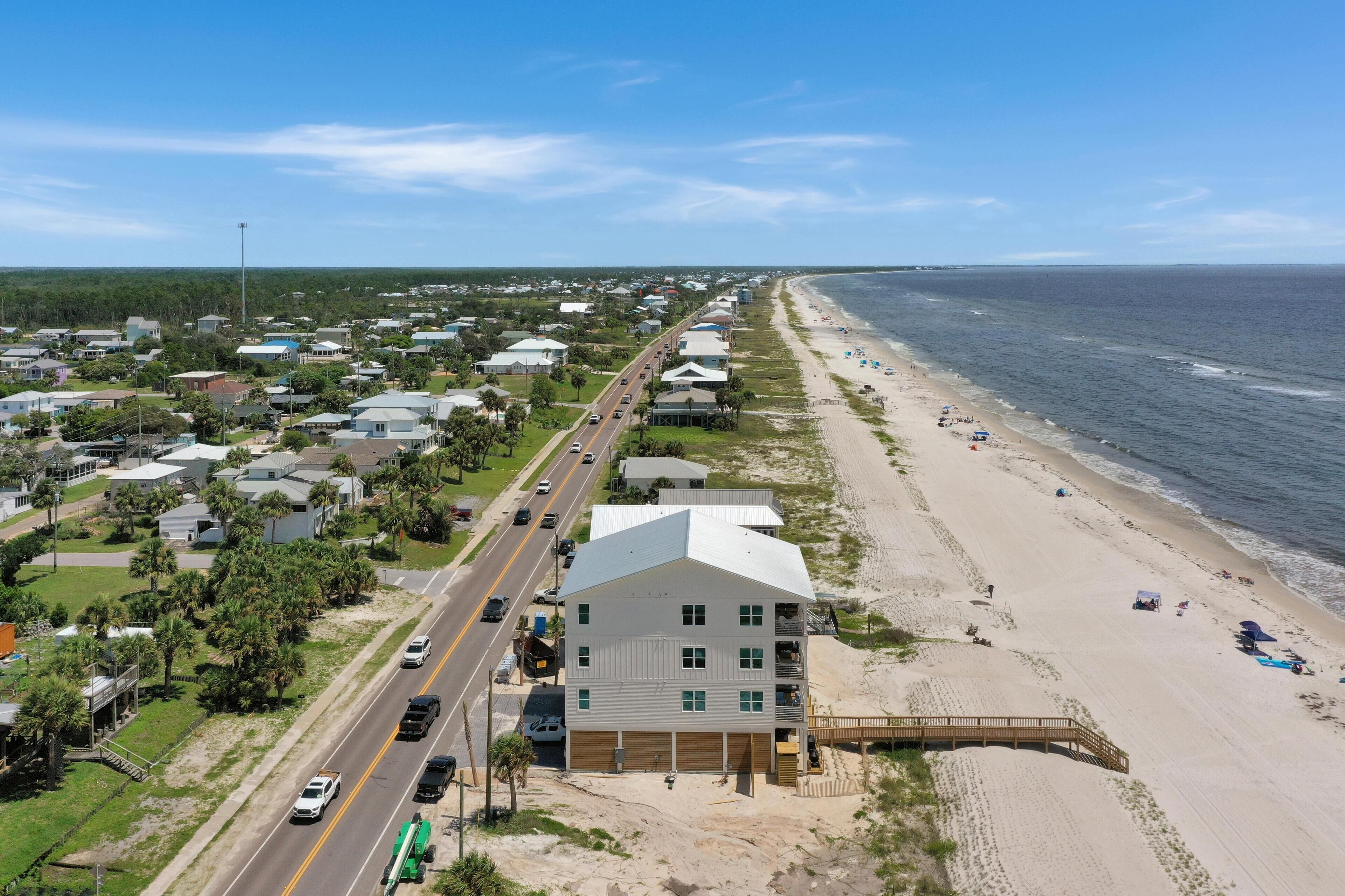 A coastal town with a beach, a main road, and residential buildings.