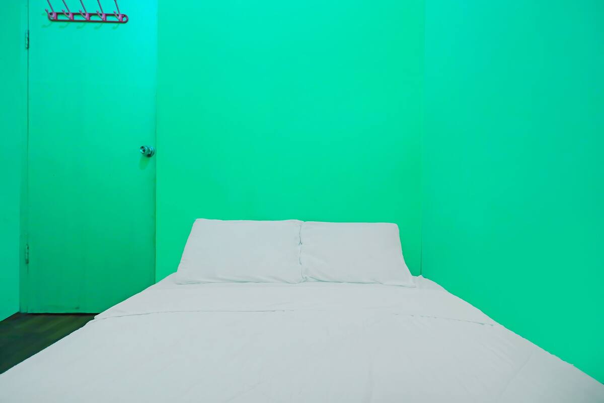 Une pièce avec un lit, une porte et un étagère fixée au mur.