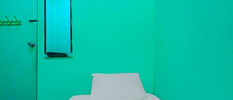 A room with a bed, a door, and a mirror.