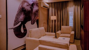 A room with a large elephant mural, two beige armchairs, a lamp, and a wooden wall. - Ikogosi Warm Springs Resort and Conference Center (Ikogosi)