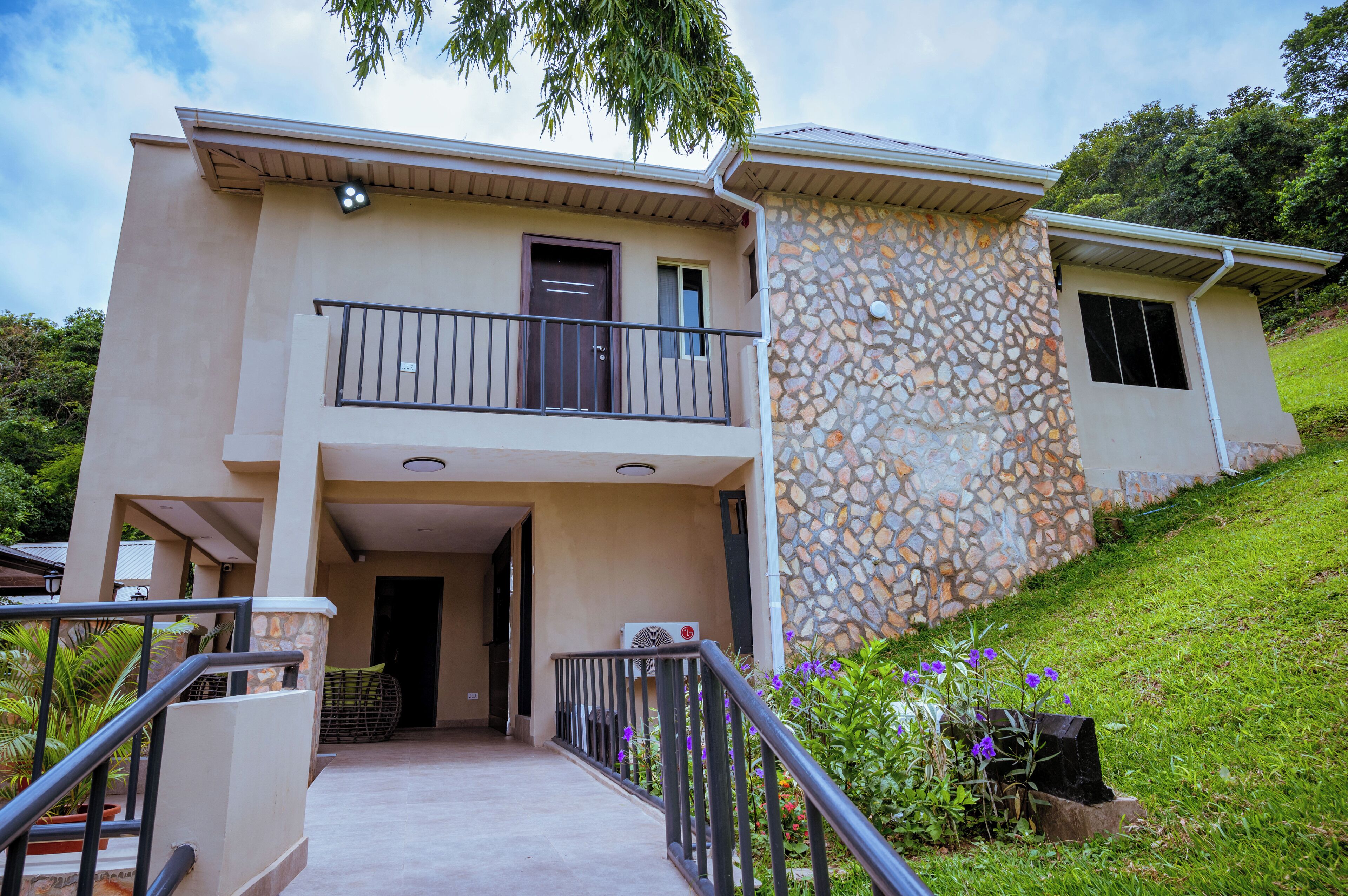 A two-story house with a balcony, a stone facade, and a front entrance.