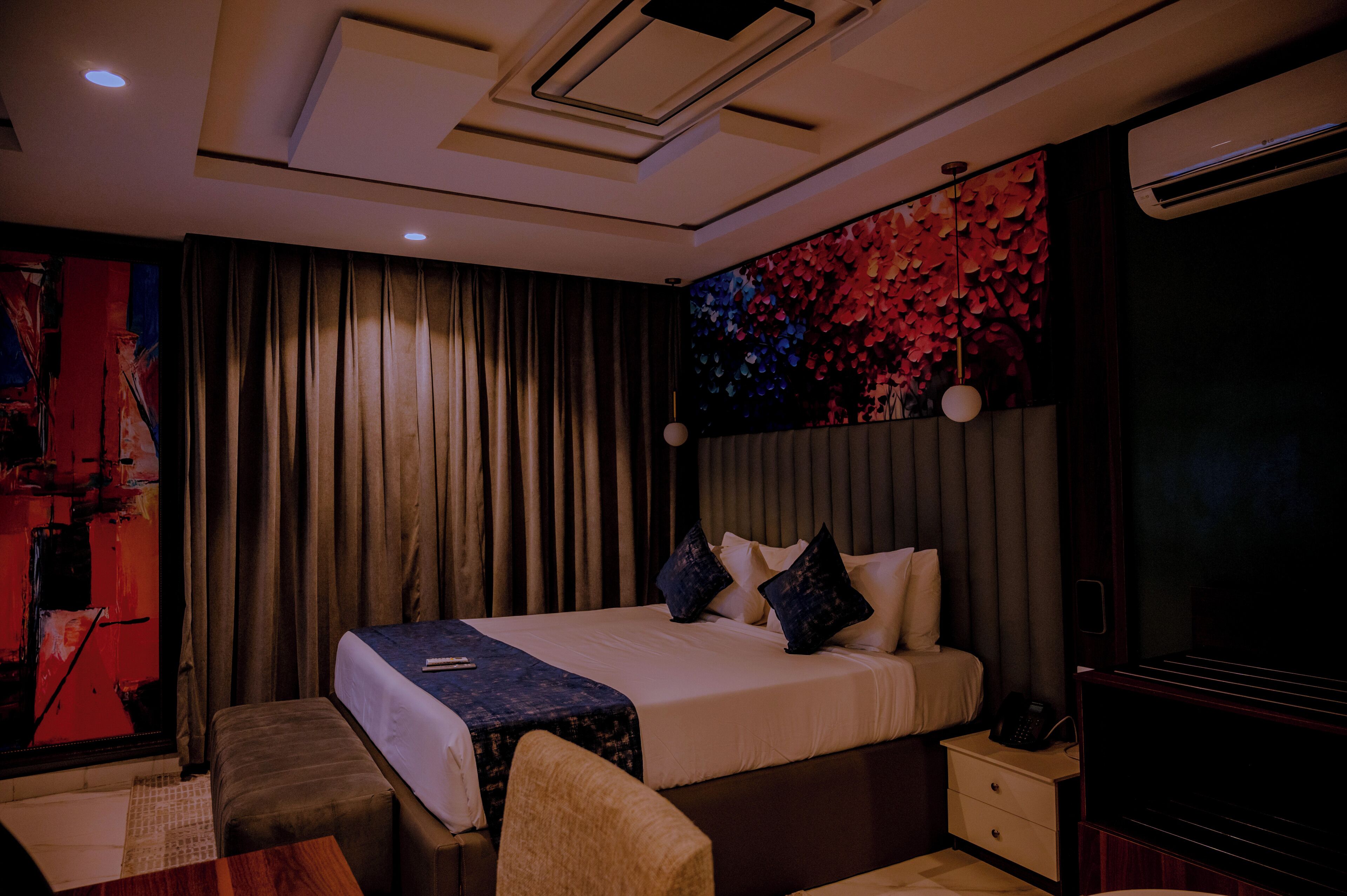 Una habitación de hotel moderna con una cama grande, una mesita de noche, una silla y una pared con un mural floral.