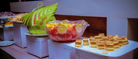 A buffet with various food items including fruits and pastries.