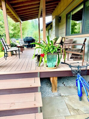 Terraza al aire libre techada con mobiliario de madera, una bicicleta y plantas en macetas.