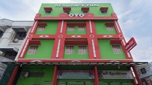 Un immeuble à plusieurs étages dont la façade porte les inscriptions « RESIDENCE PURI HOTEL » et « OYO ».