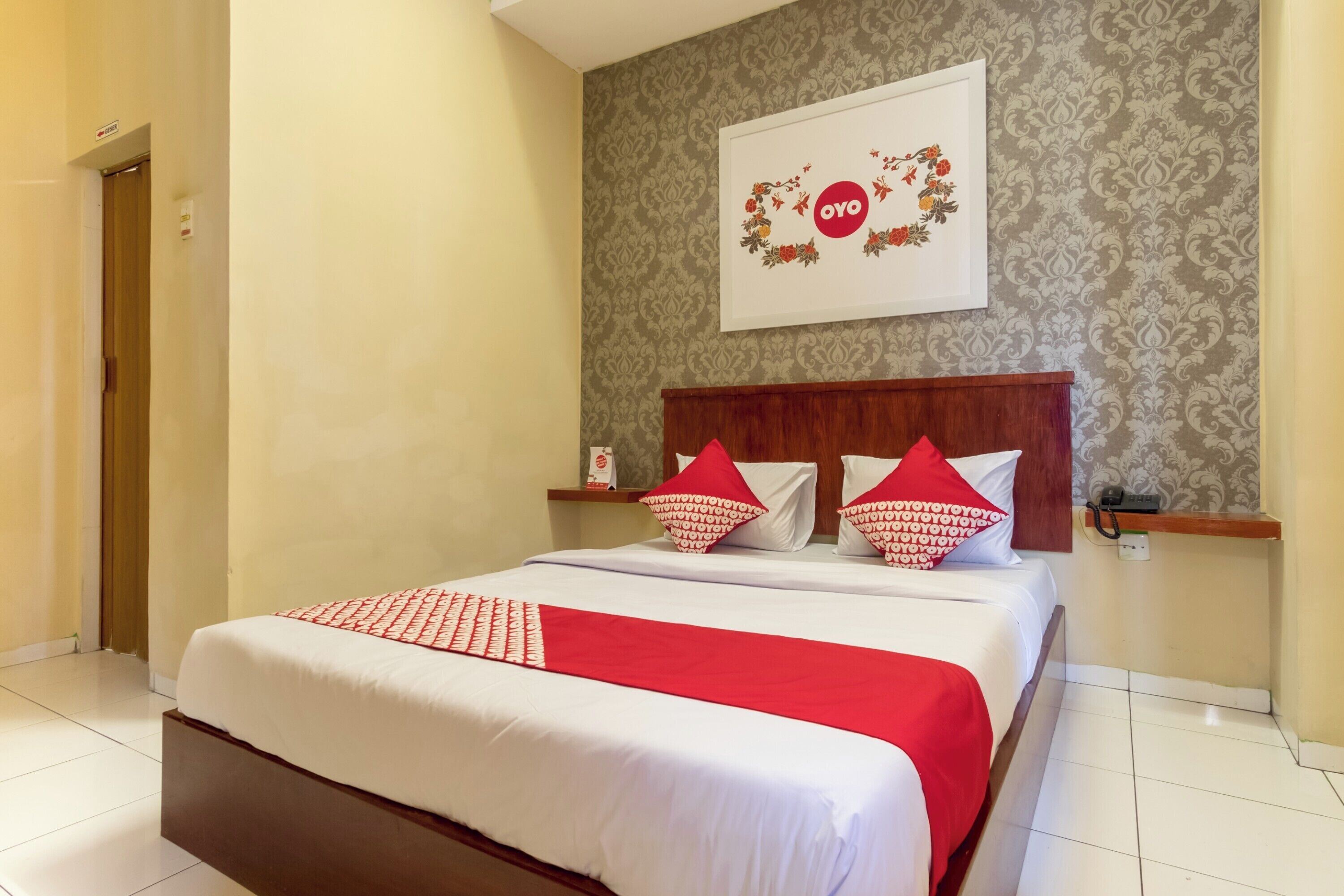 A neatly made bed with a red and white bedspread, a wooden headboard, and matching pillows.