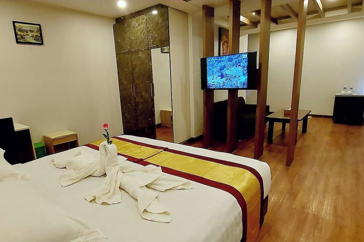 A hotel room with two beds, a television, a desk, and a mirror.