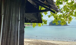 Vista de una playa con una estructura de bambú y cielo despejado.