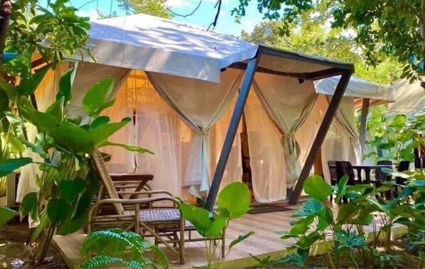Una carpa con un porche cubierto, una mesa y sillas.