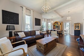 A spacious living room with a brown leather sofa, a wooden coffee table, and a dining area with a wooden cabinet and chairs. - Stylish, comfortable centrally located home! TVs in every room, cable (Omaha)