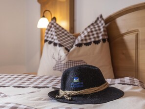 A bed with a checkered bedspread, a black hat with a logo, and two pillows with a checkered pattern.