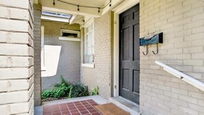 A narrow entrance with a red-tiled floor, a dark door, and a small window. - Charming Midtown Apt - Hannon Hideaway Unit A (Mobile)