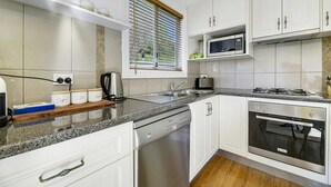 A modern kitchen with white cabinets, a built-in microwave, a gas stove, and a dishwasher. - Towac Cabin 1 • Mt Canobolas Views • Orange (Canobolas)