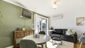 A living room with a round table, a sofa, and a television mounted on the wall. - Towac Cabin 1 • Mt Canobolas Views • Orange (Canobolas)