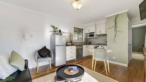 A compact living space with a kitchenette, a dining area, and a seating area. - Towac Cabin 1 • Mt Canobolas Views • Orange (Canobolas)